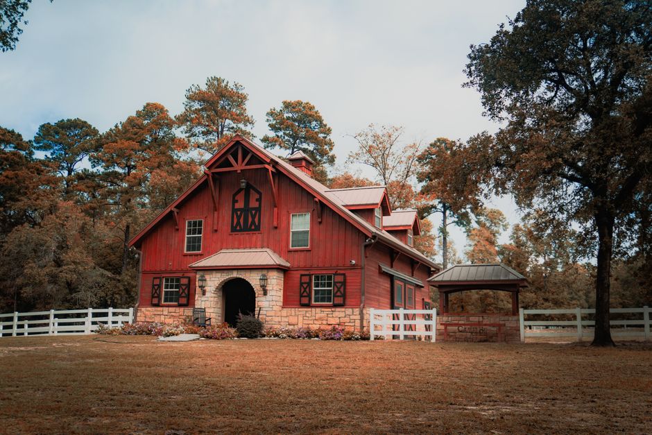 Red barndominium with living quarters and white fence in NC countryside — metal building kit by Heavy Duty Metal Buildings