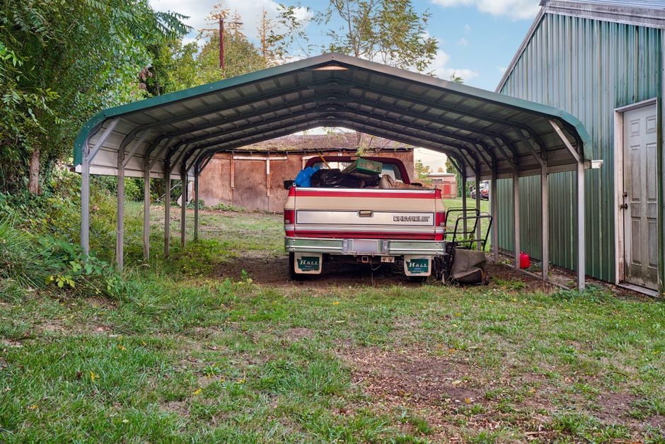 Metal carport sheltering a pickup truck in a rural NC setting, ideal for farm and property owners in Raleigh, NC